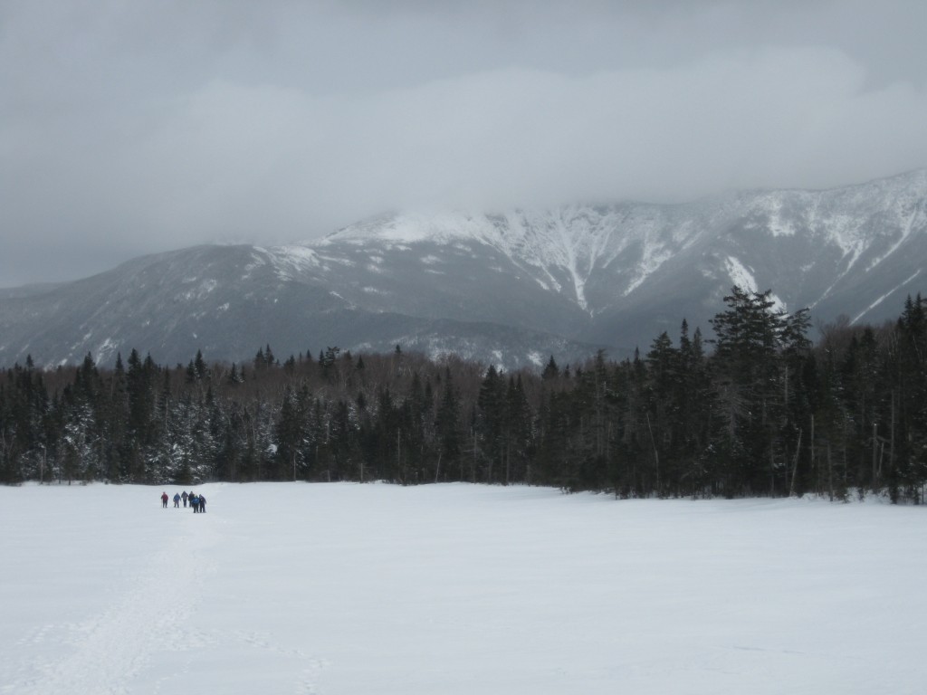 Winter hikers cross a very frozen Lonesome Lake to a backdrop of the majestic Franconia Ridge